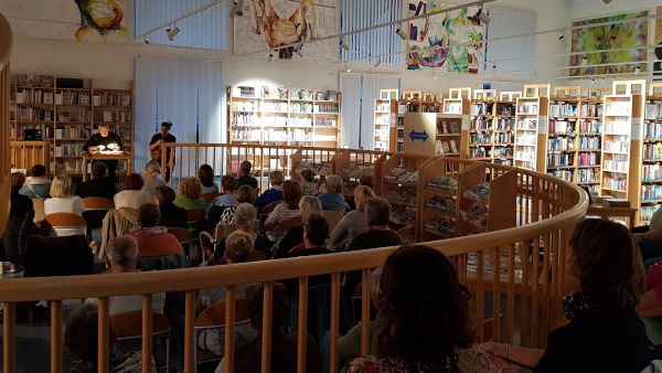 Stefan Franke liest in der vollen Stadtbücherei Schwechat historische Zeitungsberichte über Schwechat.